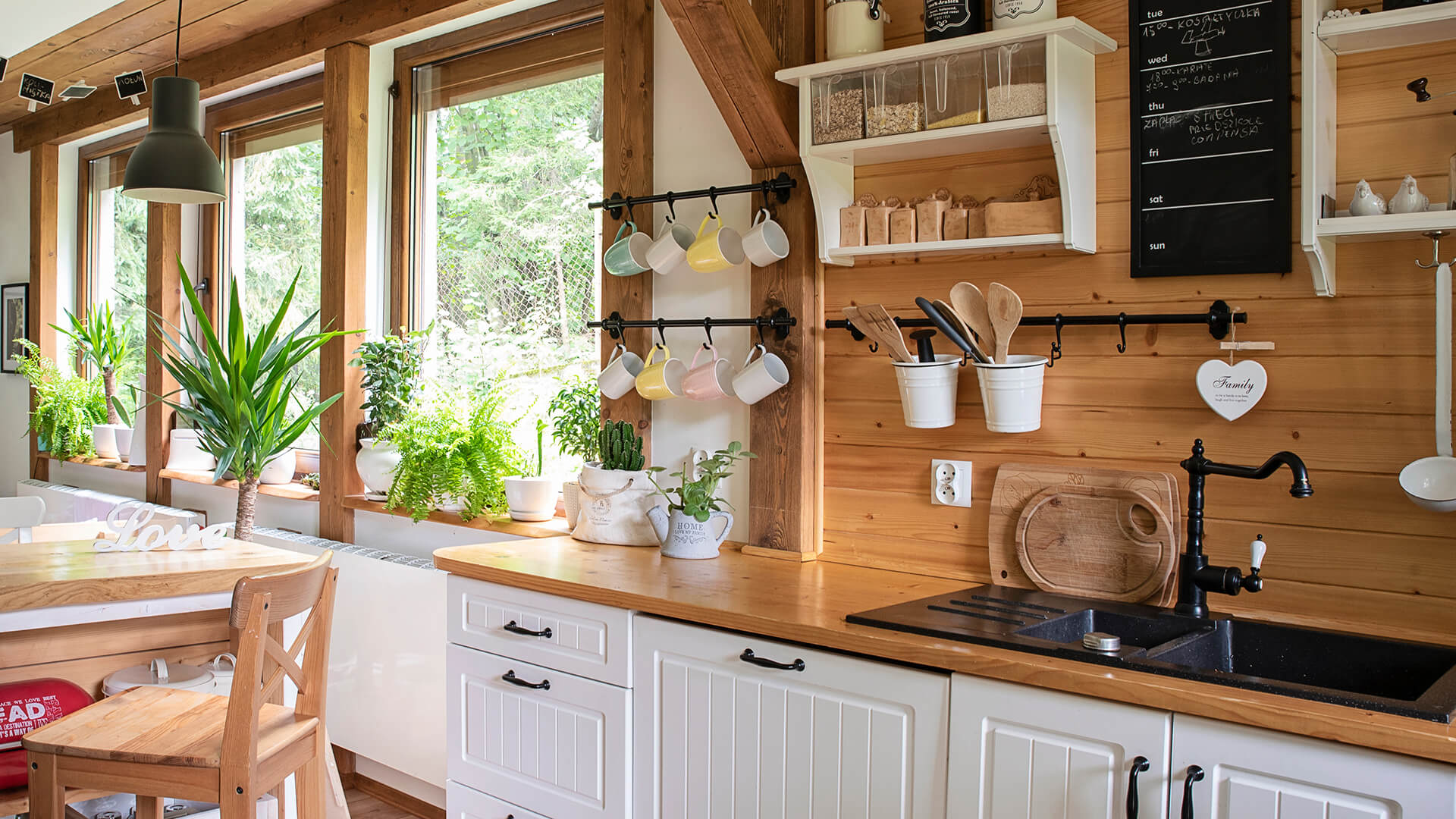 Küche mit Holz, weißen Schränken, Pflanzen und Tassen