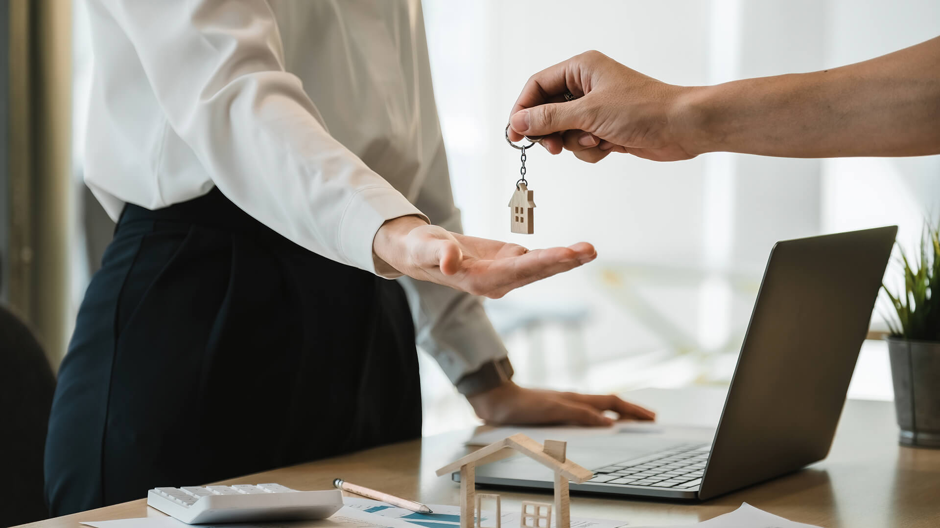 Hausübergabe mit Schlüsseln, Laptop und Dokumenten im Büro