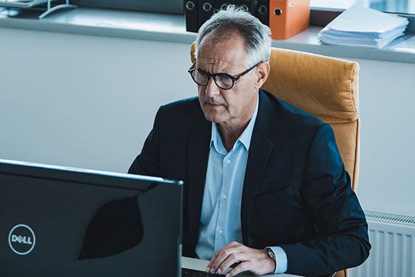 Mann mit Anzug und Brille arbeitet am Computer im Büro