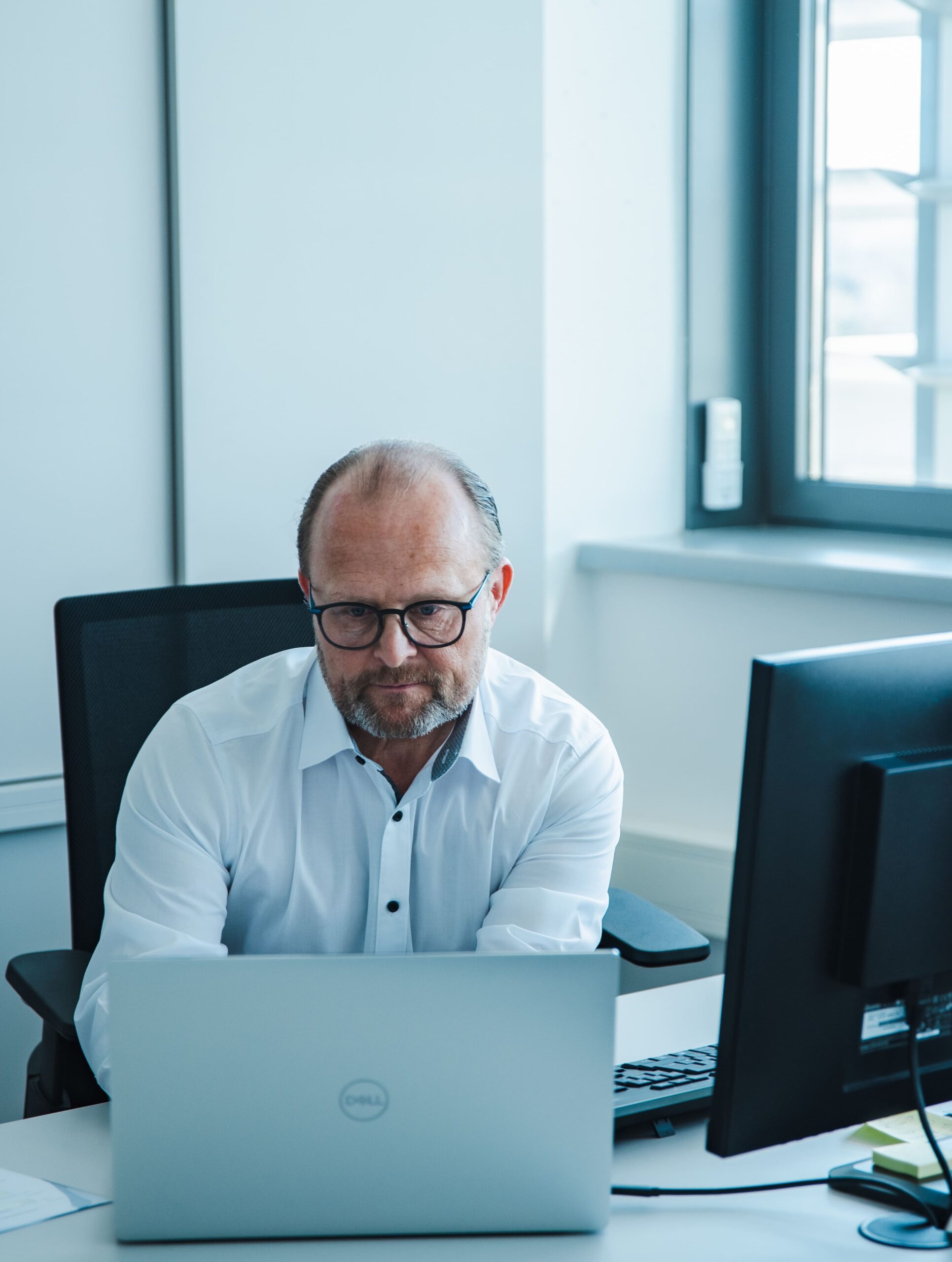 Mann mit Brille arbeitet am Schreibtisch im hellen Büro