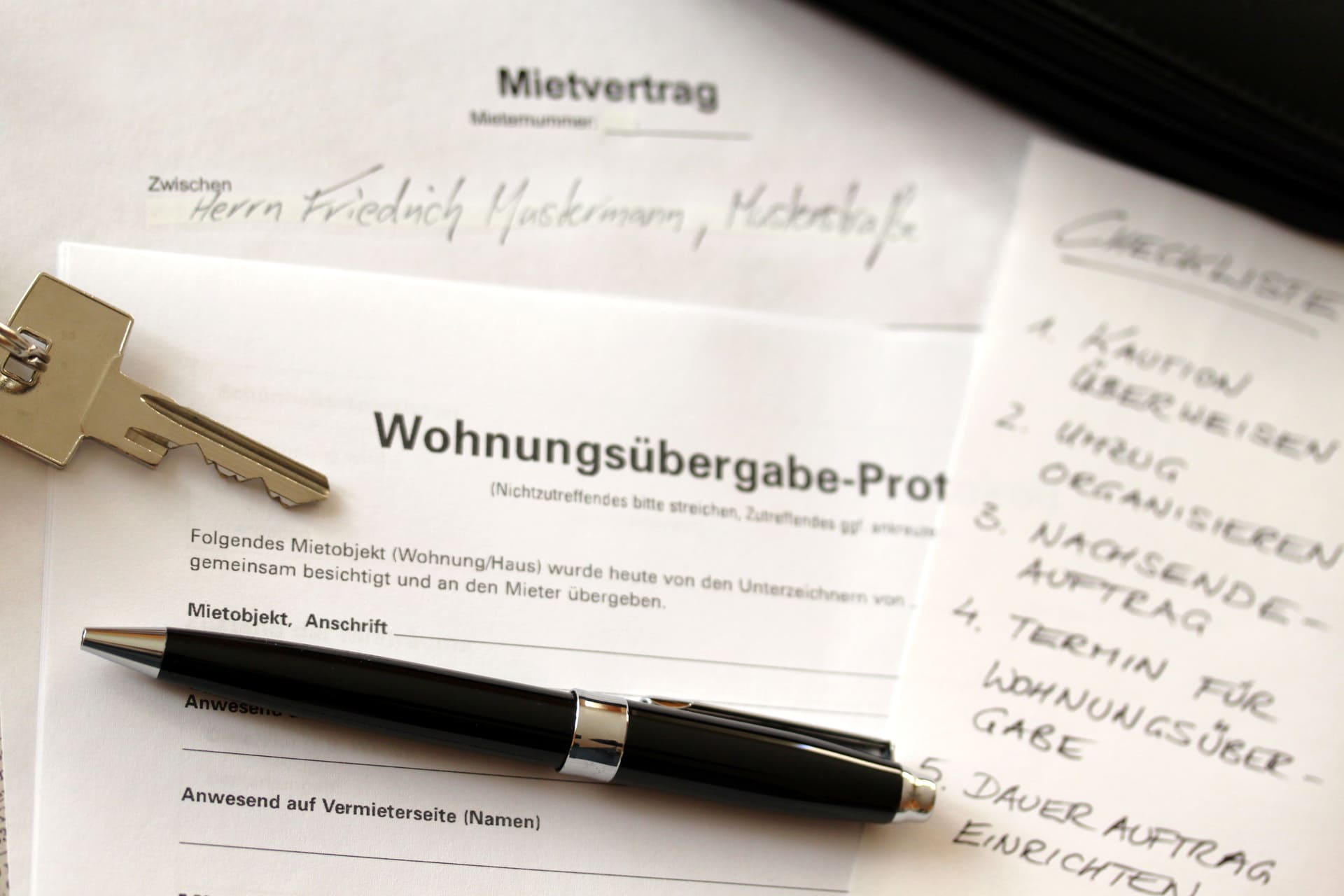 Mietvertrag mit Wohnungsübergabe-Protokoll, Schlüssel und Stift auf einem Tisch.