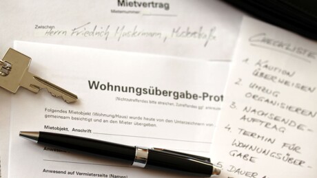 Mietvertrag mit Wohnungsübergabe-Protokoll, Schlüssel und Stift auf einem Tisch