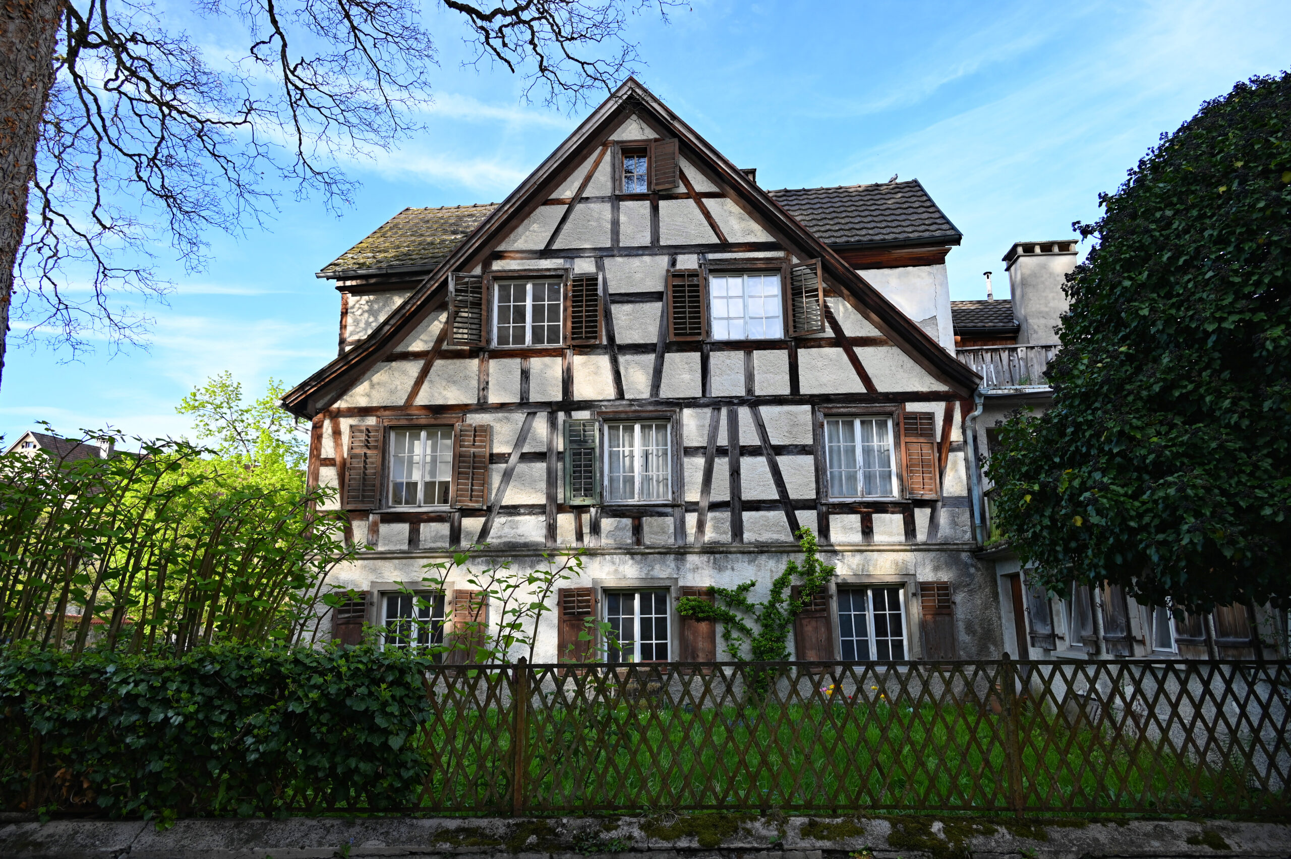 Historisches mehrstöckiges Fachwerkhaus mit Holzläden und Vorgartenzaun.