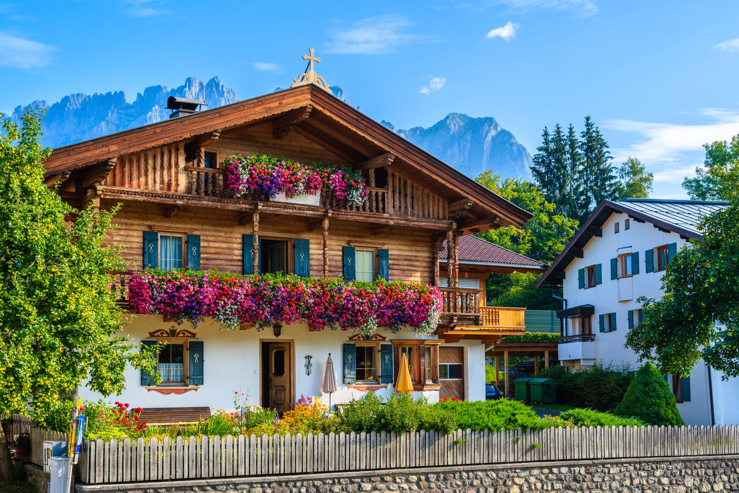 Traditionelles Tiroler Landhaus mit Blumenschmuck vor alpiner Bergkulisse.