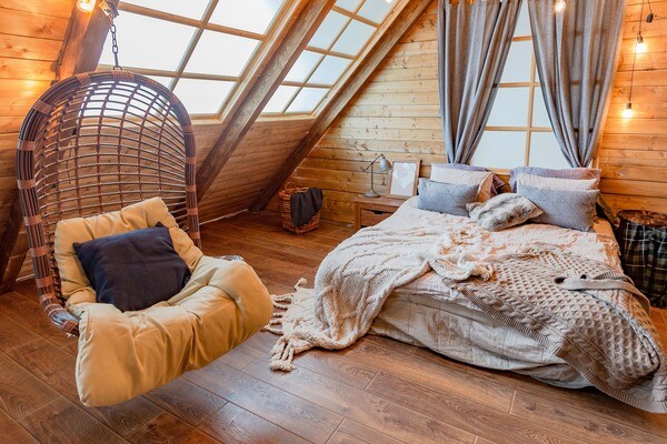 Gemütliches Dachgeschoss-Schlafzimmer im Holz-Chalet mit Hängesessel.