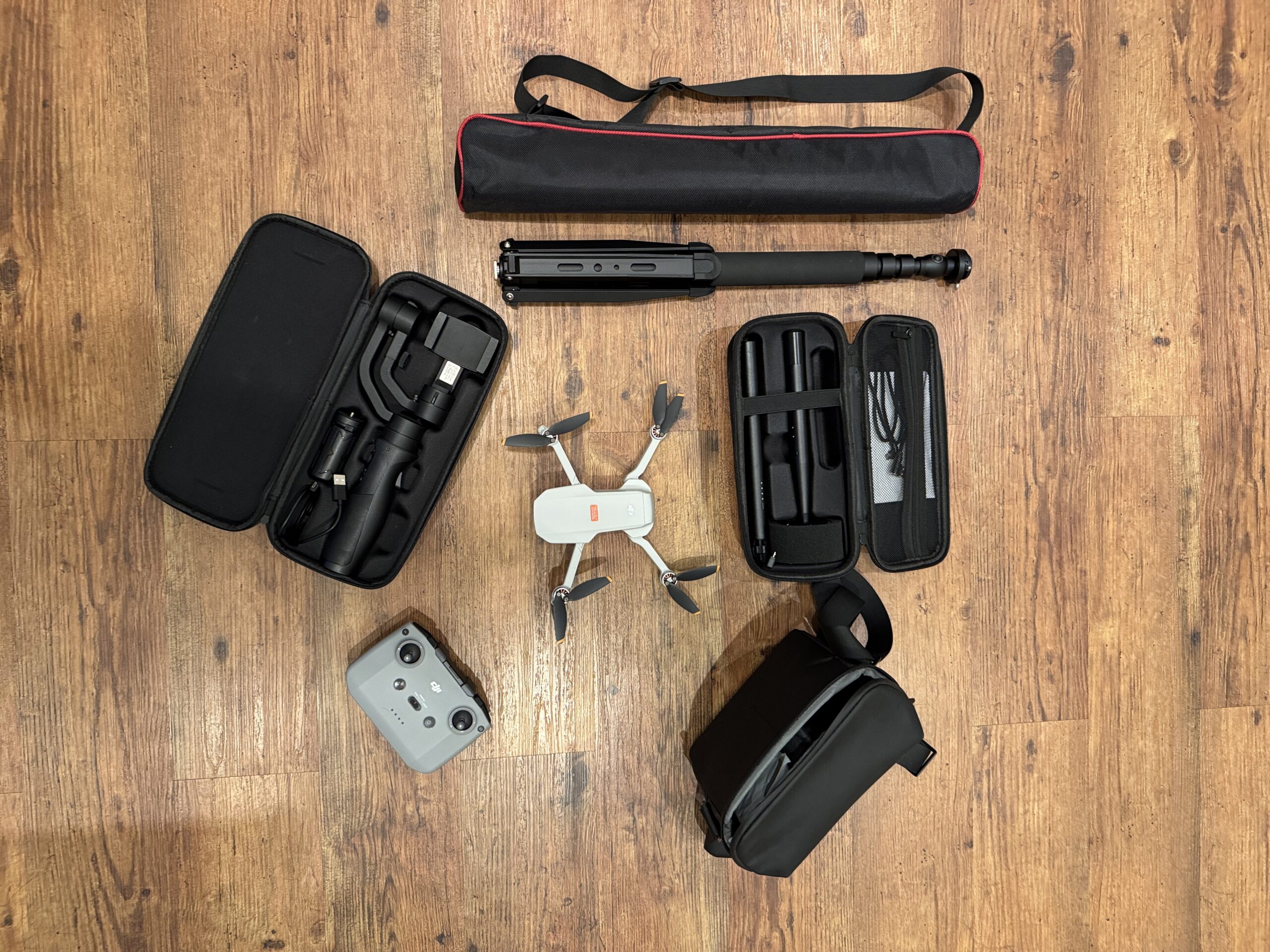 Drohne, Kameraausrüstung und Taschen auf Holzboden von oben.