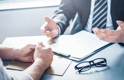 Zwei Personen im Business-Look am Schreibtisch mit Dokumenten.