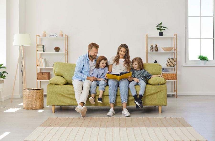 Eltern lesen ihren zwei Kindern auf einem Sofa im Wohnzimmer vor.