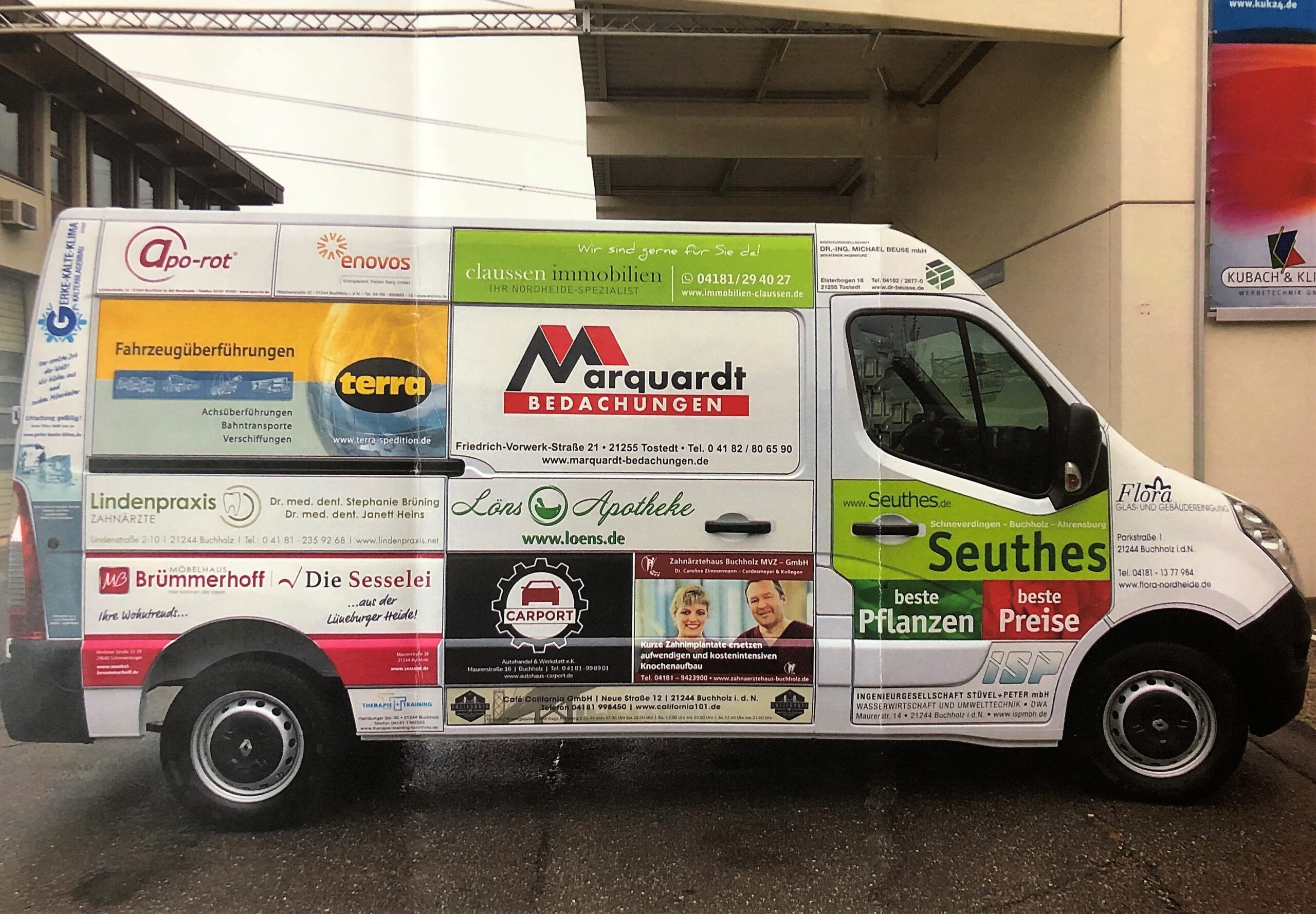 Weißer Transporter mit zahlreichen bunten Werbeaufklebern verschiedener lokaler Unternehmen und Dienstleistungen auf der Seite