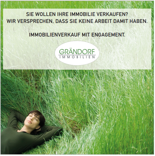 Frau liegt im Gras unter dem Schild von Grándorf Immobilien.