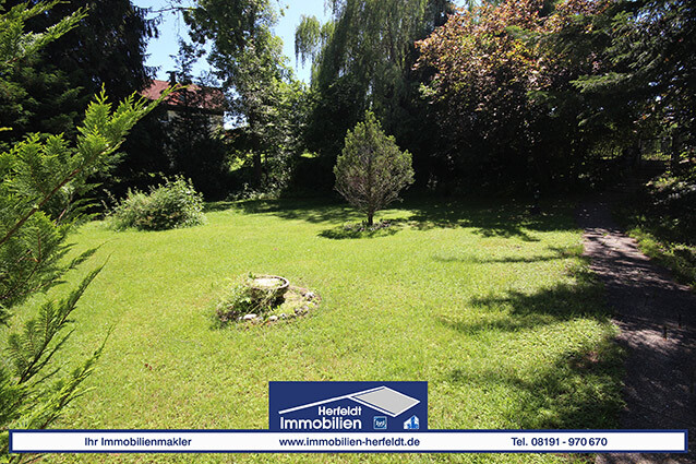 Garten mit grünem Rasen, Bäumen, Sträuchern und Vogelbad.