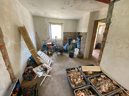 Renovierungsraum mit Sichtziegeln, Werkzeugen, Behältern und Stühlen.