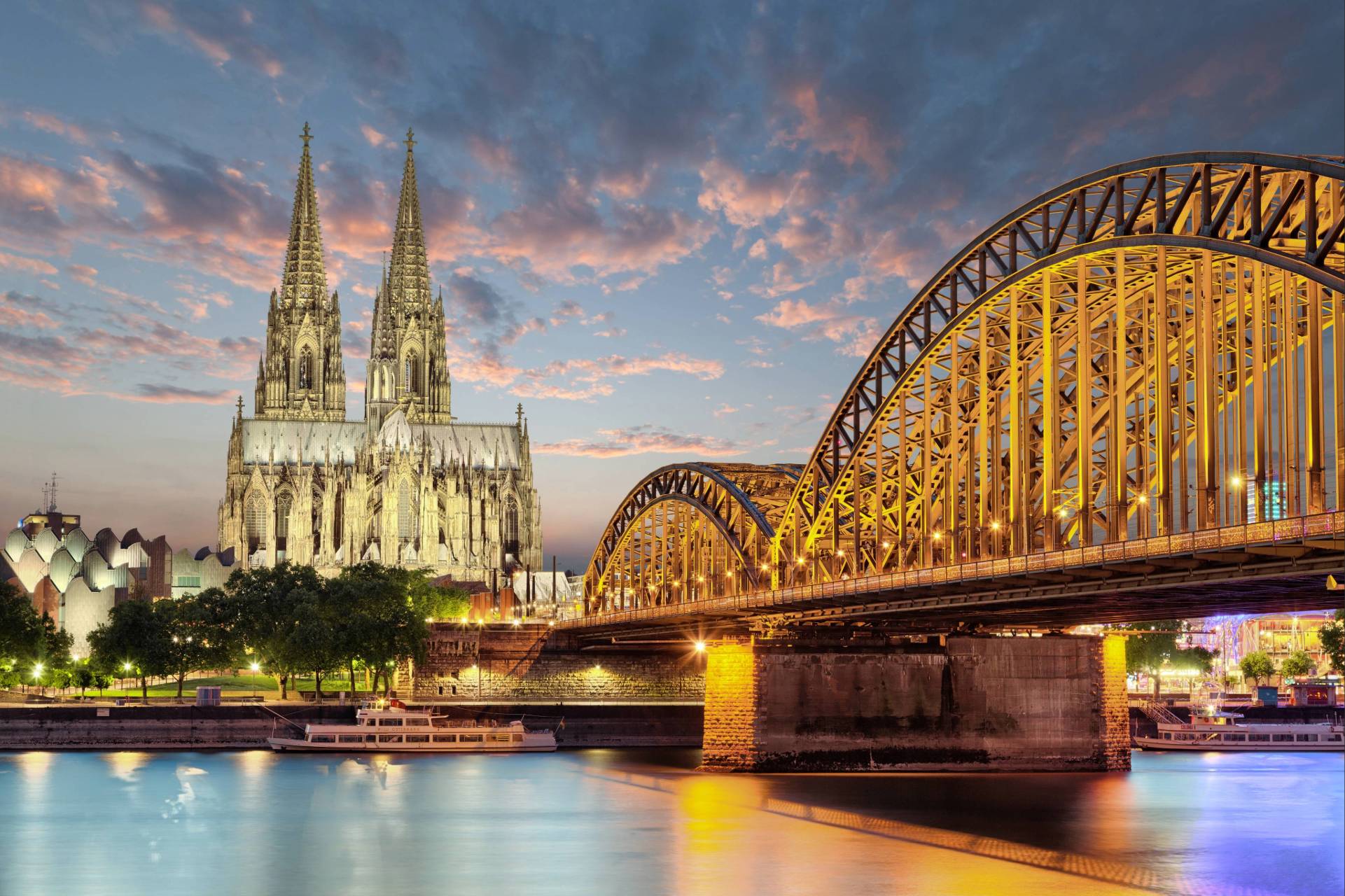 Blick auf den Kölner Dom und die Hohenzollernbrücke bei Abenddämmerung.