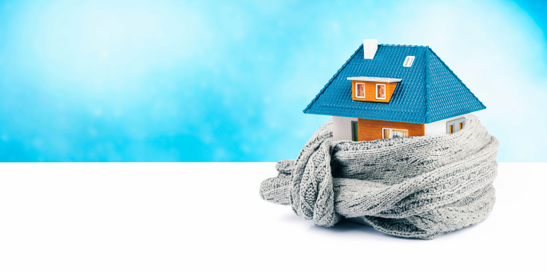 Hausmodell mit Schal vor blauem Hintergrund