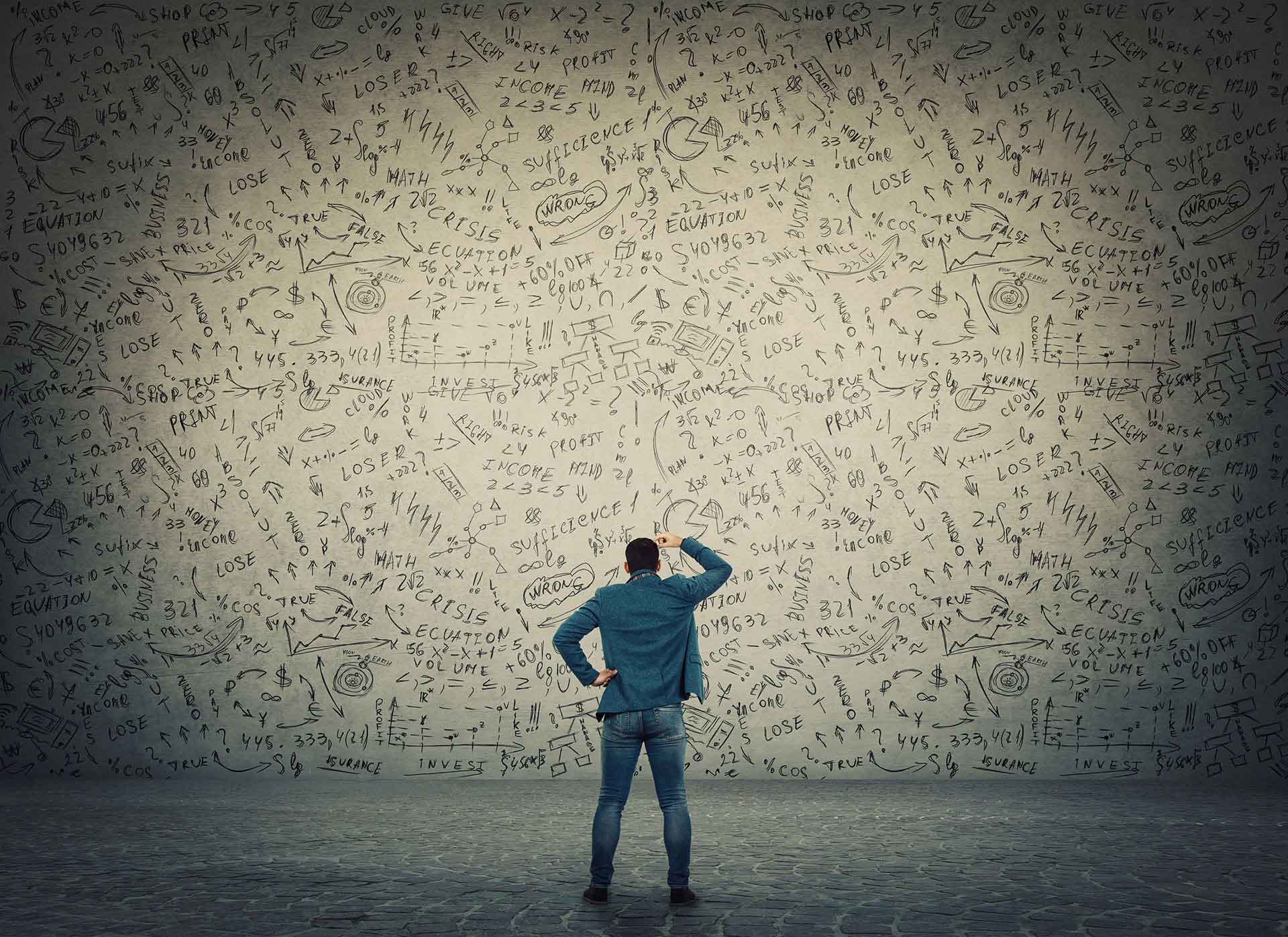 Verwirrter Mann vor chaotisch bekritzelter Wand.