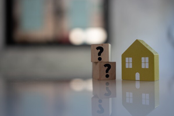 Würfel mit Fragezeichen neben Modellhaus