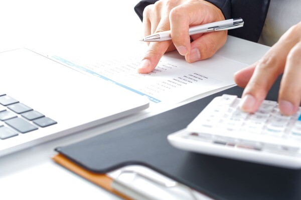 Makler bestimmt Verkaufspreis mit Taschenrechner