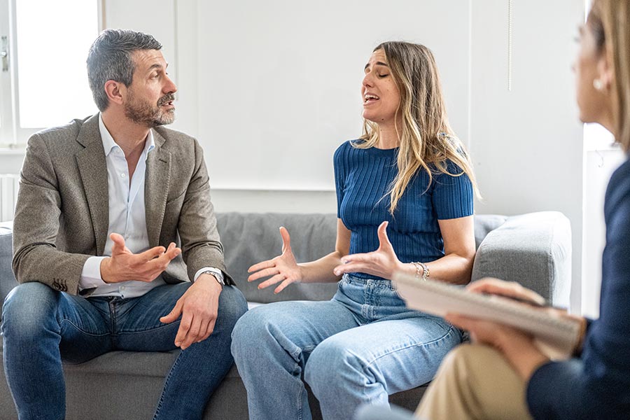 Streitends Paar im Gespräch auf einer Couch.
