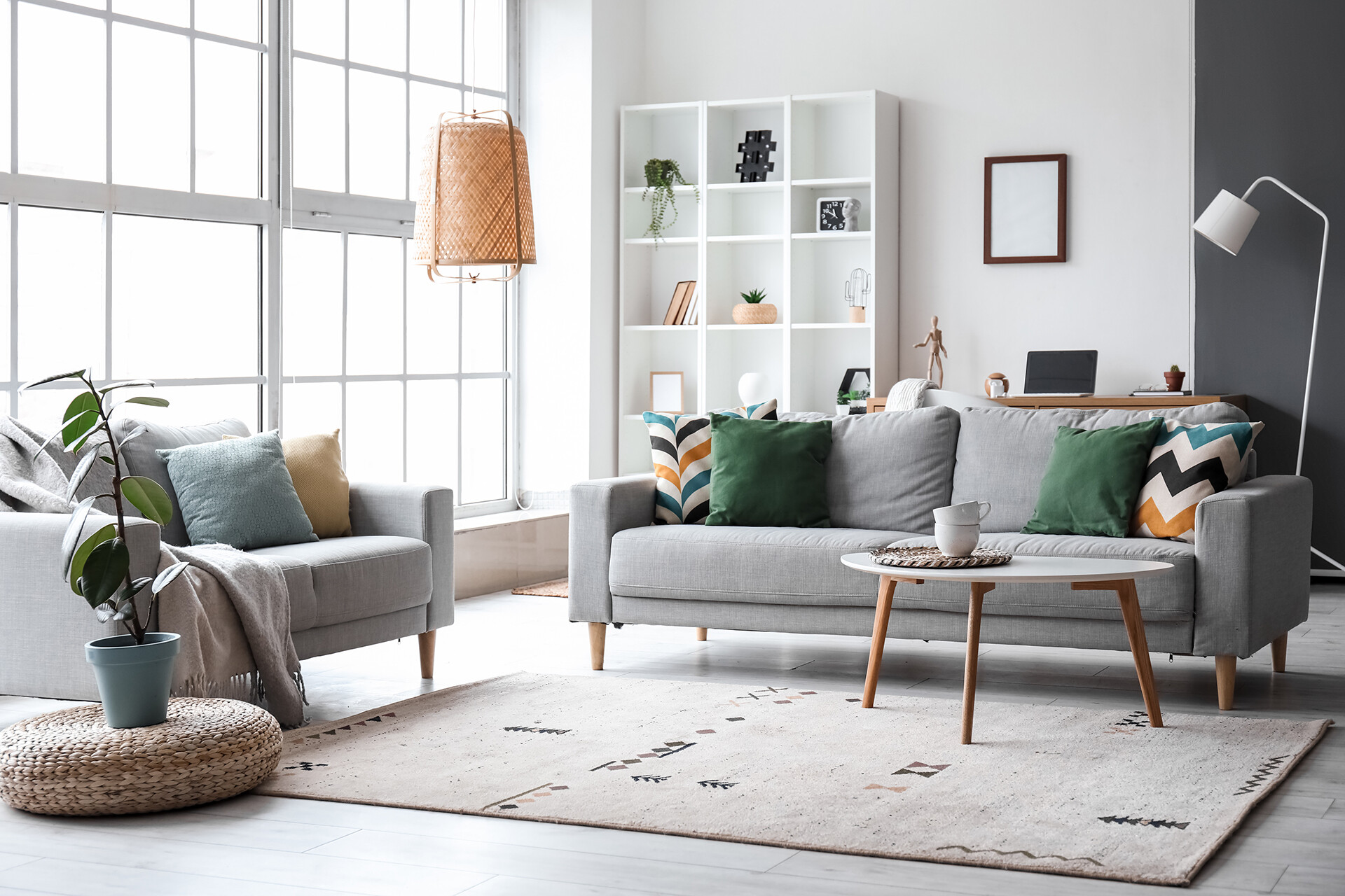 Modernes Wohnzimmer mit grauen Sofas, großem Fenster und Regalwand in stilvoller Einrichtung.
