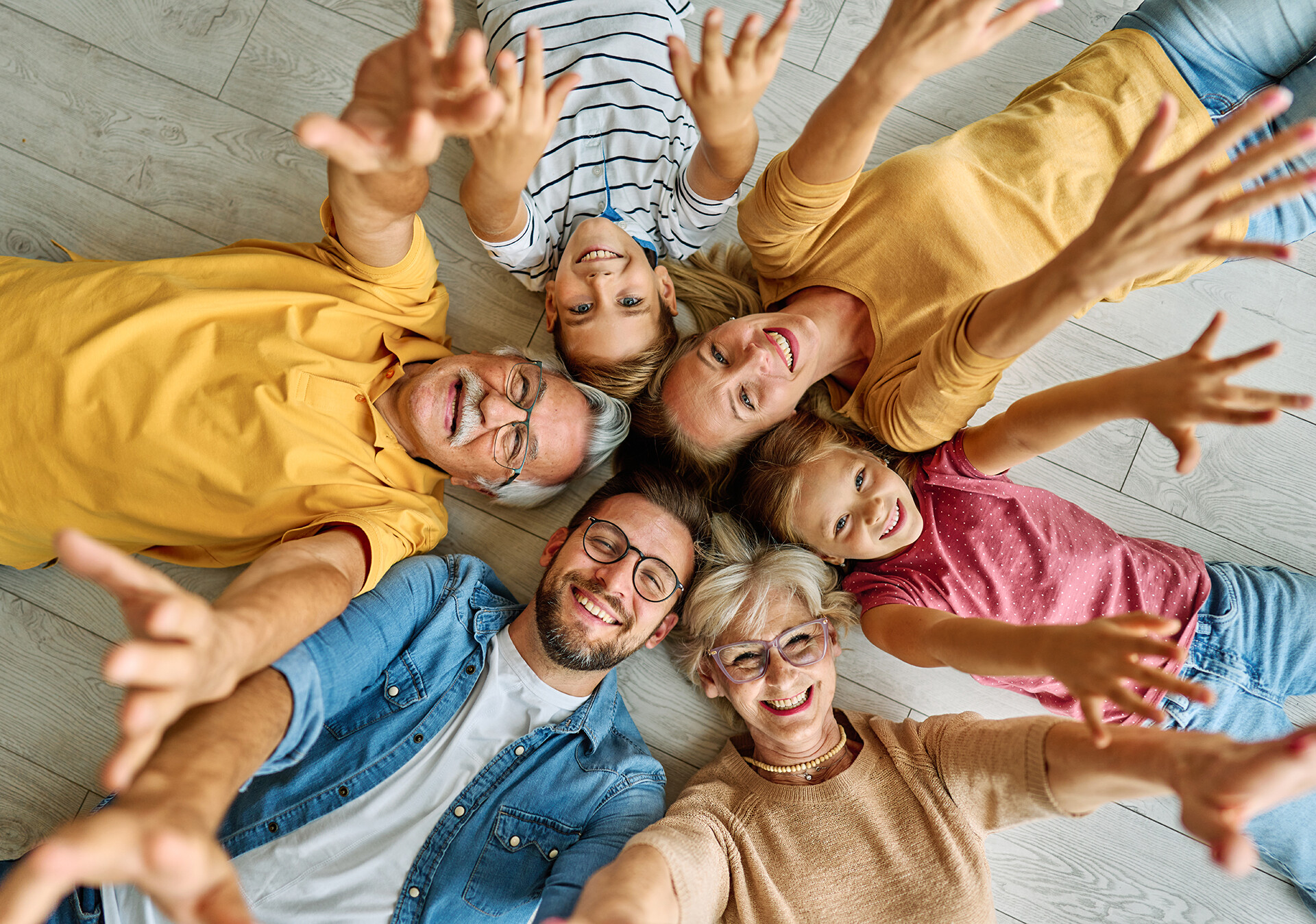 Mehrgenerationenfamilie mit Großeltern, Eltern und Kindern lächelt in die Kamera.