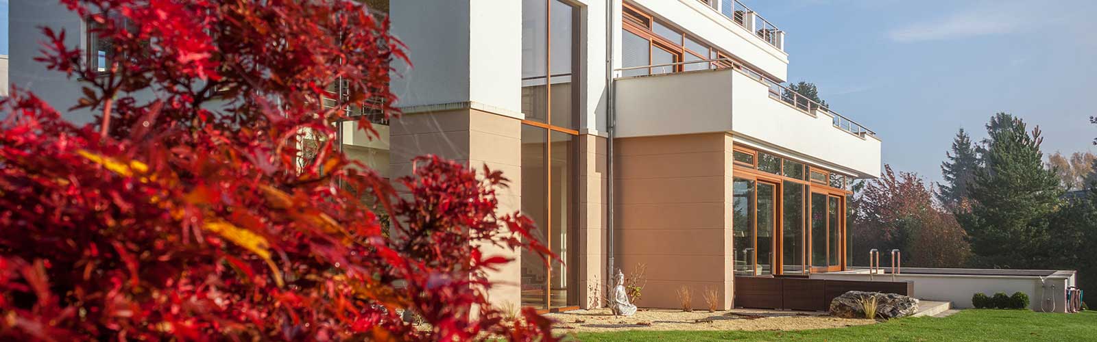 Außenansicht eines Hauses mit Buddha Statue und Bäumen im Vordergrund.