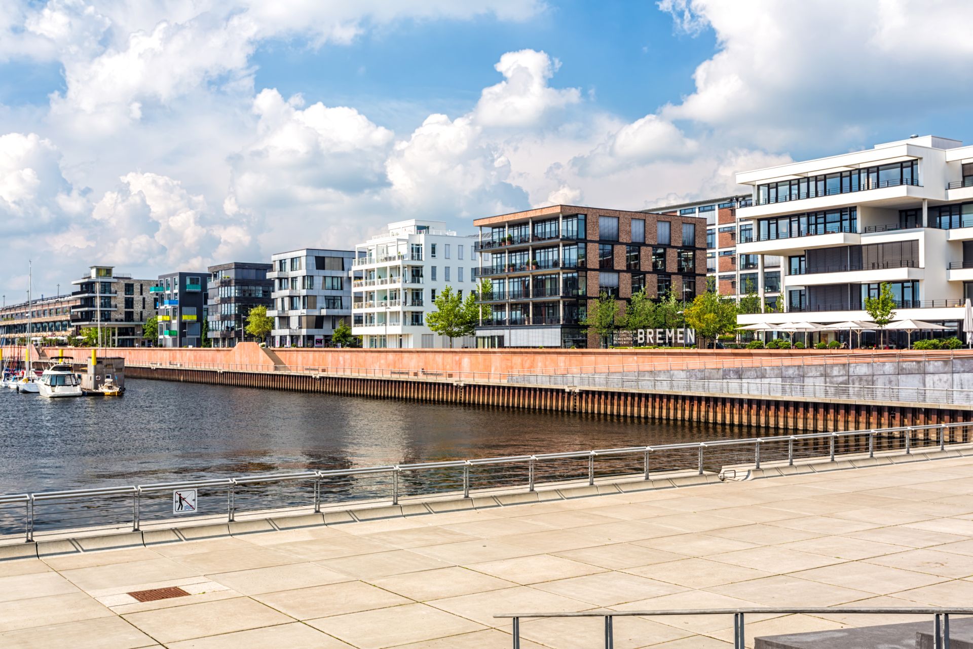 Wohnhäuser am Flussufer in Bremen bei leicht bewölktem Himmel.