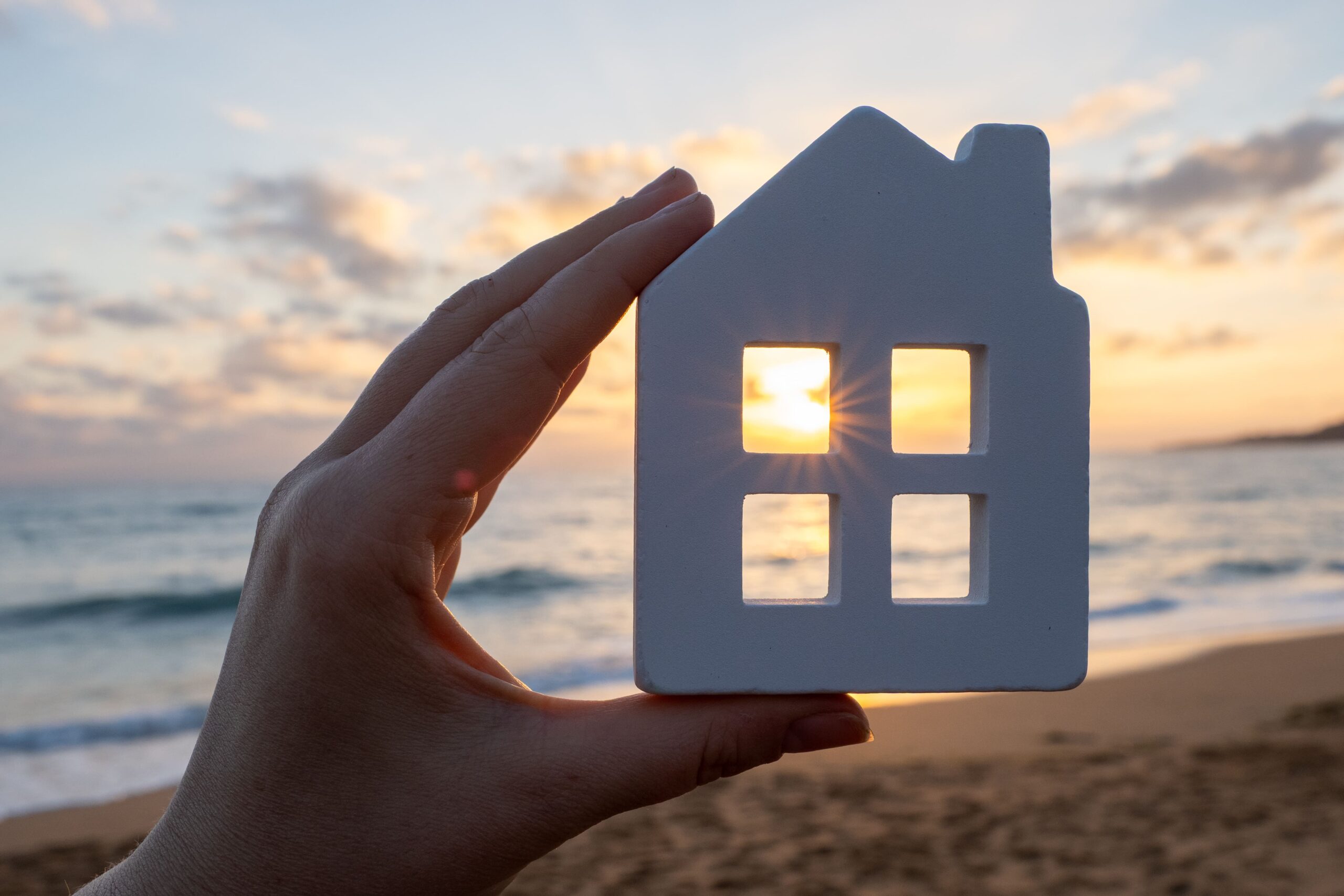 Eine Hand hält ein Miniaturhaus am Stand