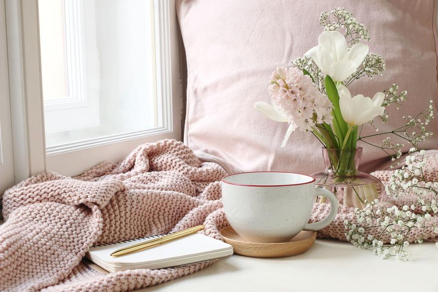 Tasse, Notizblock und Blumenstrauß in Vase.