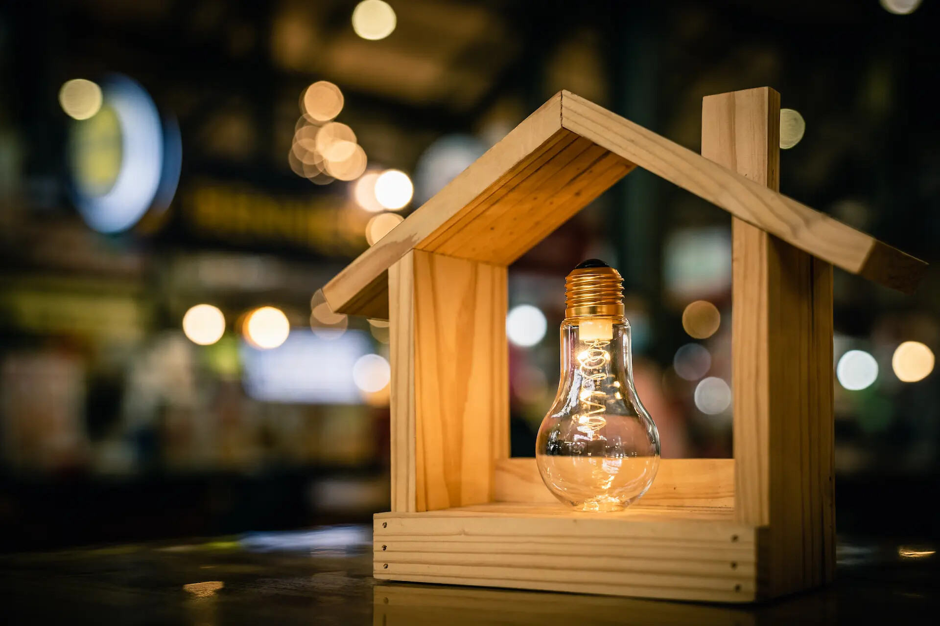 Light bulb with wood house on the table, a symbol for construction, Creative light bulb idea, power energy or business idea concept ecology, loan, mortgage, property or home.