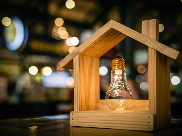 Light bulb with wood house on the table, a symbol for construction, Creative light bulb idea, power energy or business idea concept ecology, loan, mortgage, property or home.