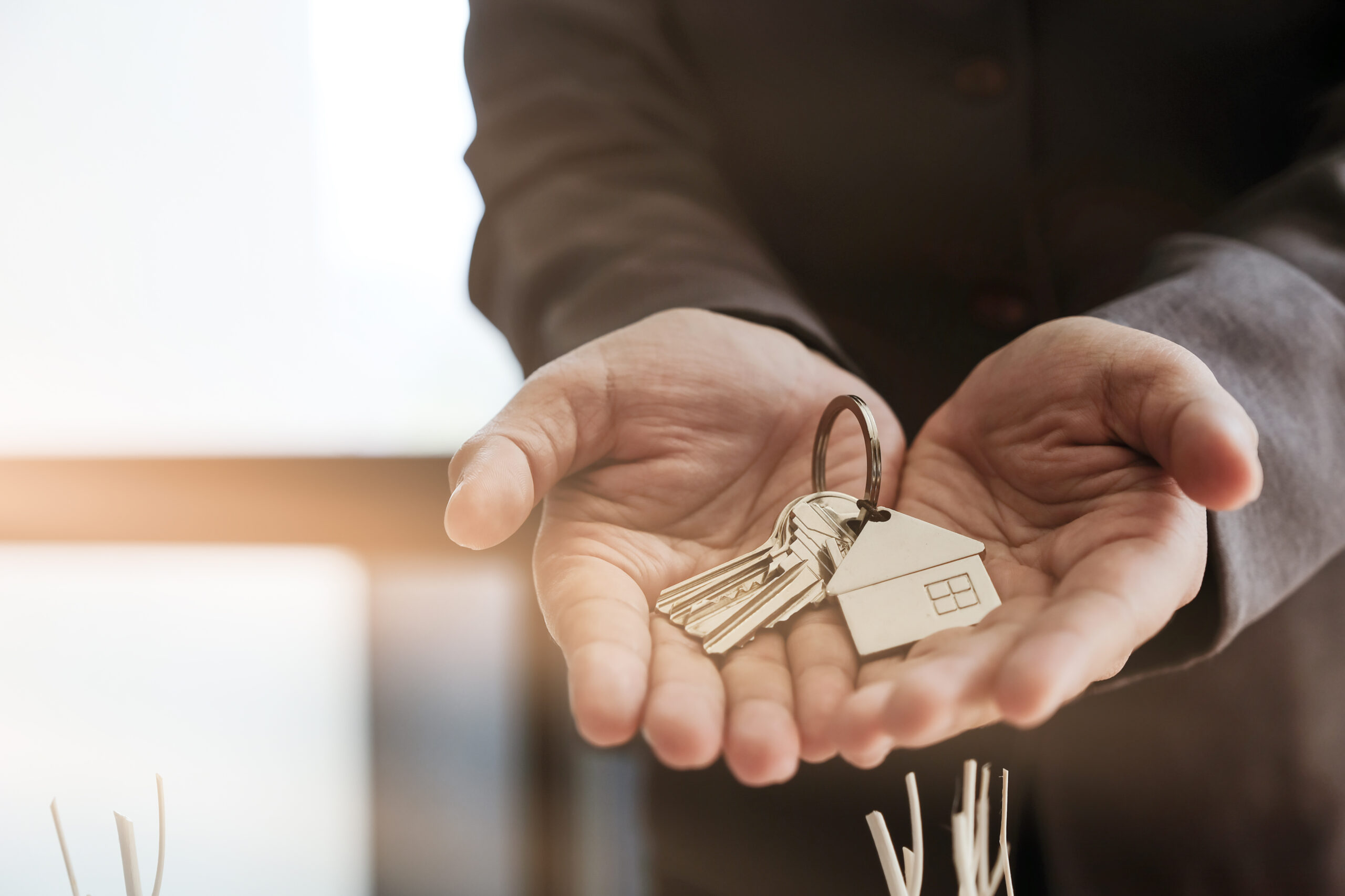 Real estate agent handing over house keys with approved mortgage application form and offer handshake