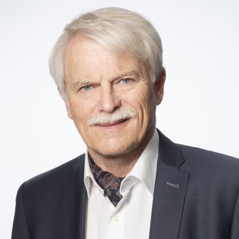 Herr Jansen mit weißem Haar und Anzug lächelt leicht.