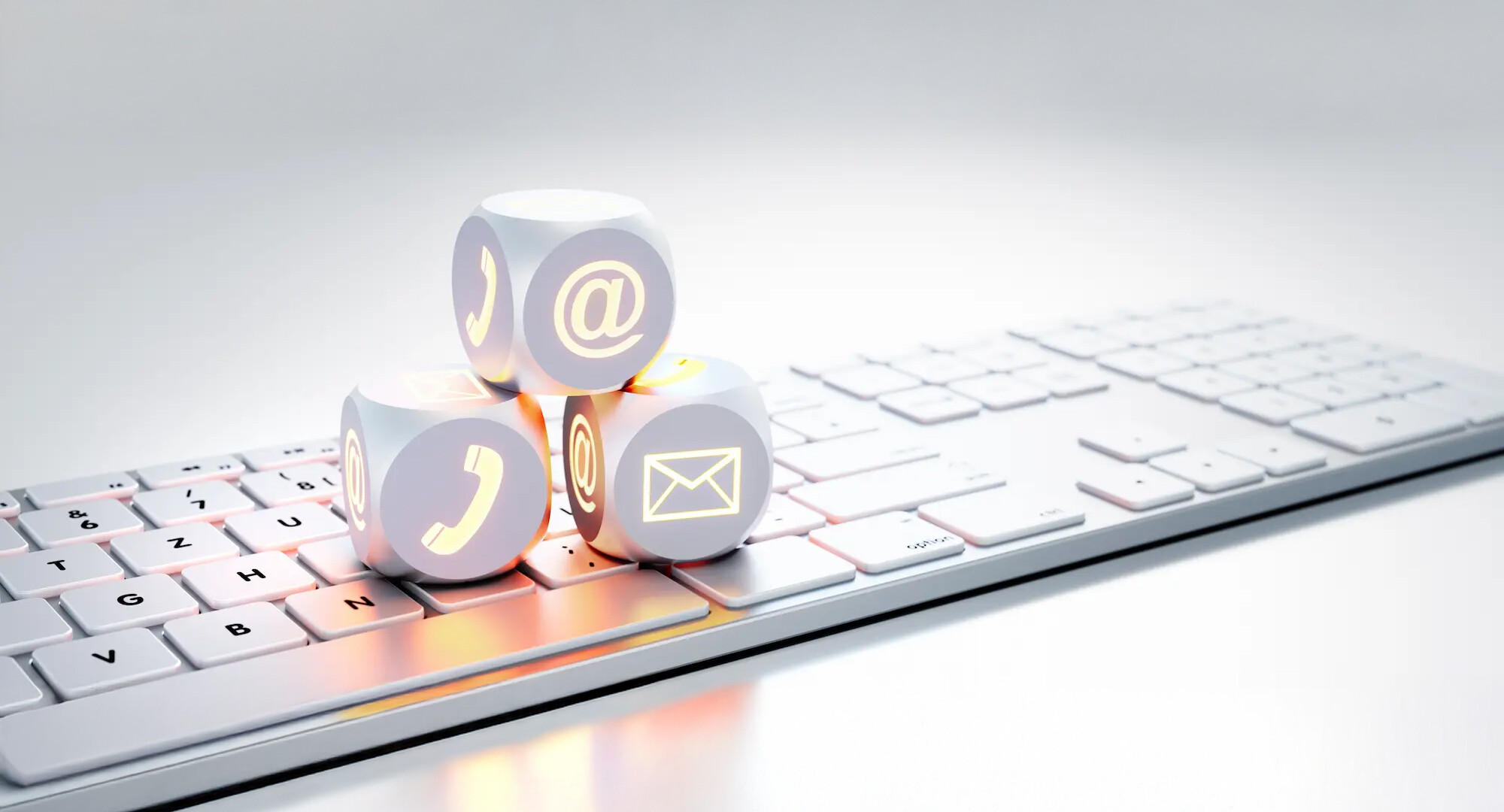 Würfel mit Telefon-, E-Mail- und @-Symbolen auf Tastatur.
