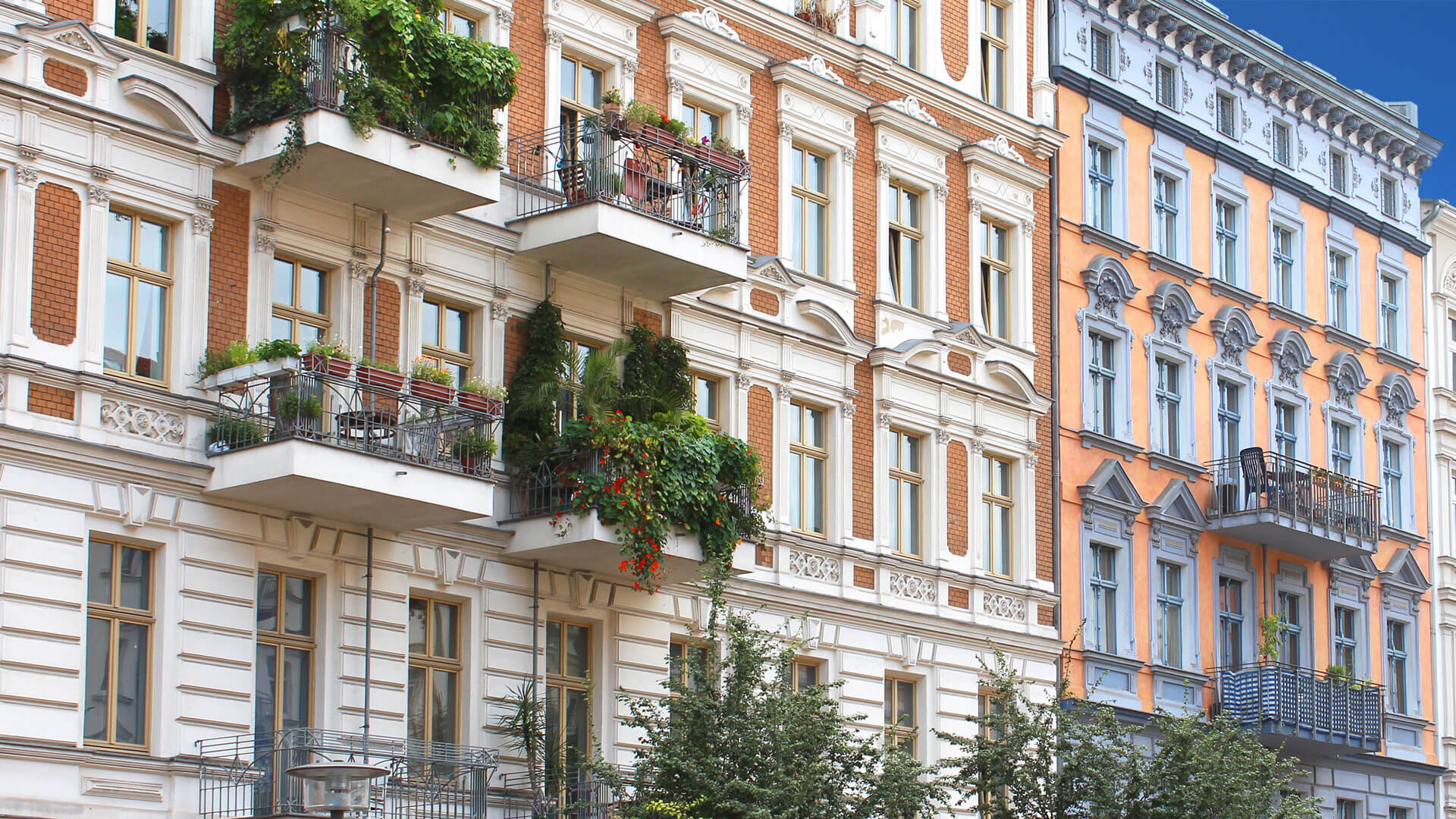 Wohnungen mit Balkonen, Pflanzen und blauem Himmel.