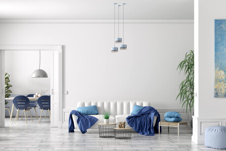 Wohnzimmer mit weißem Sofa, blauen Akzenten und Pflanzen.