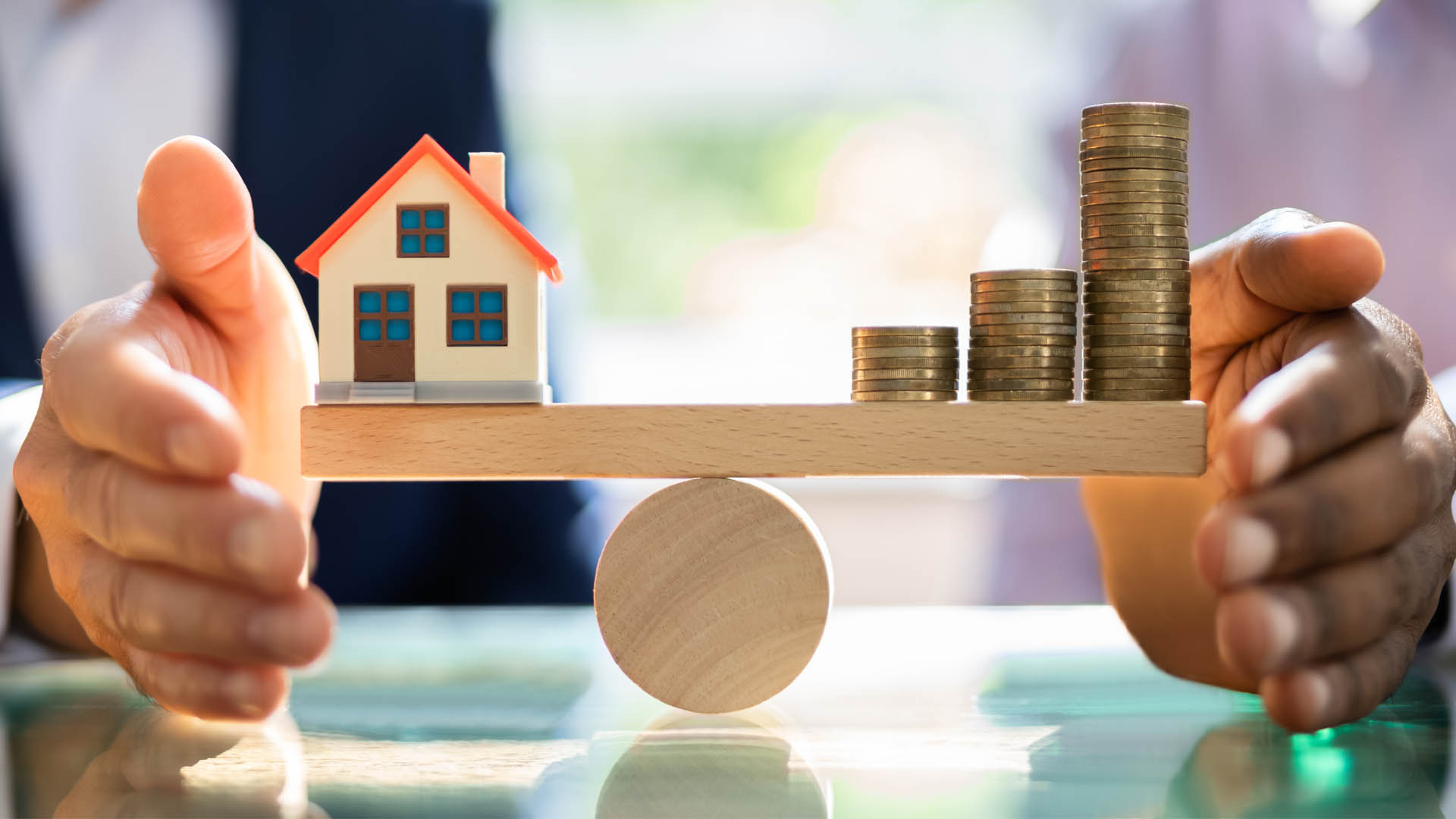 Modellhaus und Münzen auf Waage