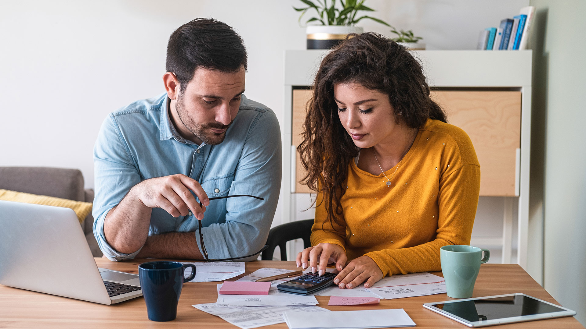 Ein Mann und eine Frau sitzen nebeneinander an einem Tisch und berechnen etwas mit einem Taschenrechner