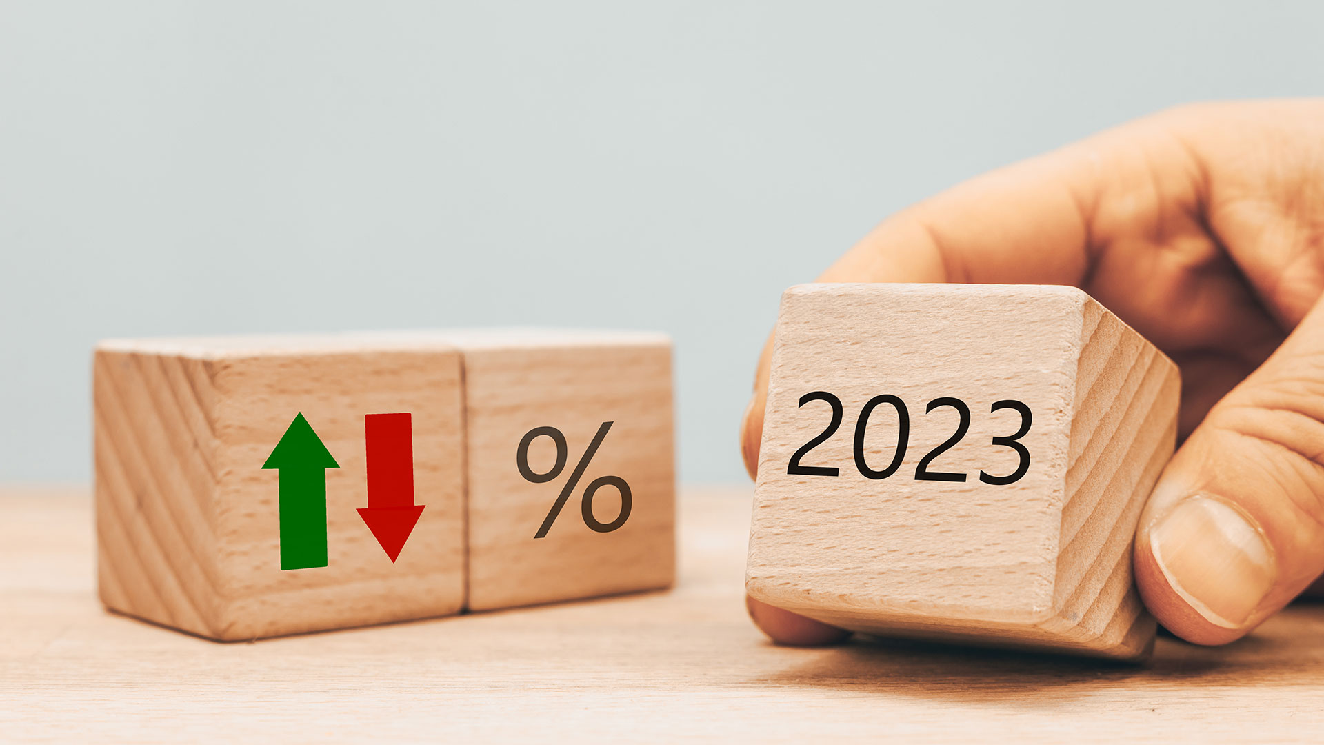 Drei Holzwürfel mit Rot und grünen Pfeilen, Prozentzeichen und der Aufschrift "2023"