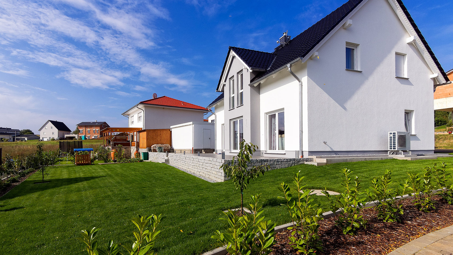 Blick auf eine Wohnsiedlung, im Vordergrund ein modernes, weißes Einfamilienhaus