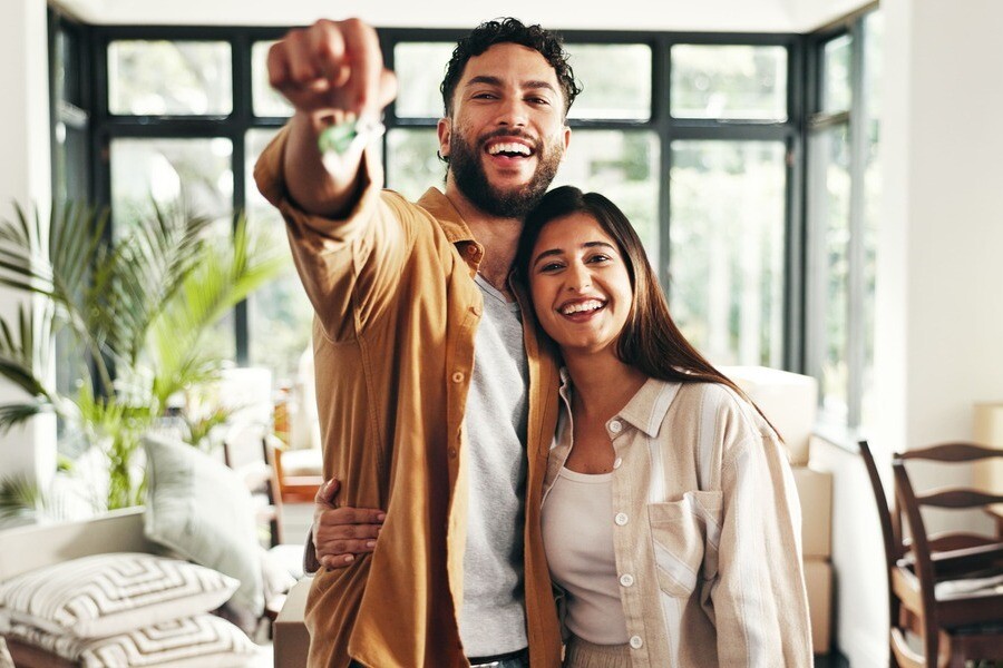 Ein Paar steht Arm in Arm und hält einen Schlüssel in die Höhe