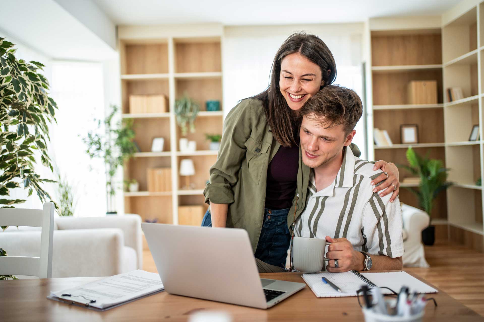 Junges Paar mit Laptop am Tisch informiert sich über die Anschlussfinanzierung des Hauses