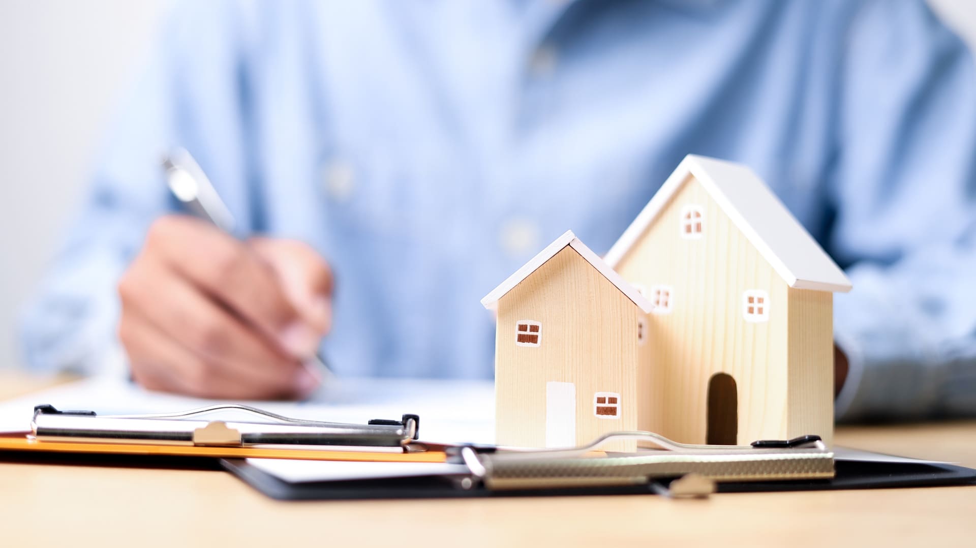 Dokumente zur Immobilienfinanzierung mit Modellhaus auf einem Schreibtisch.