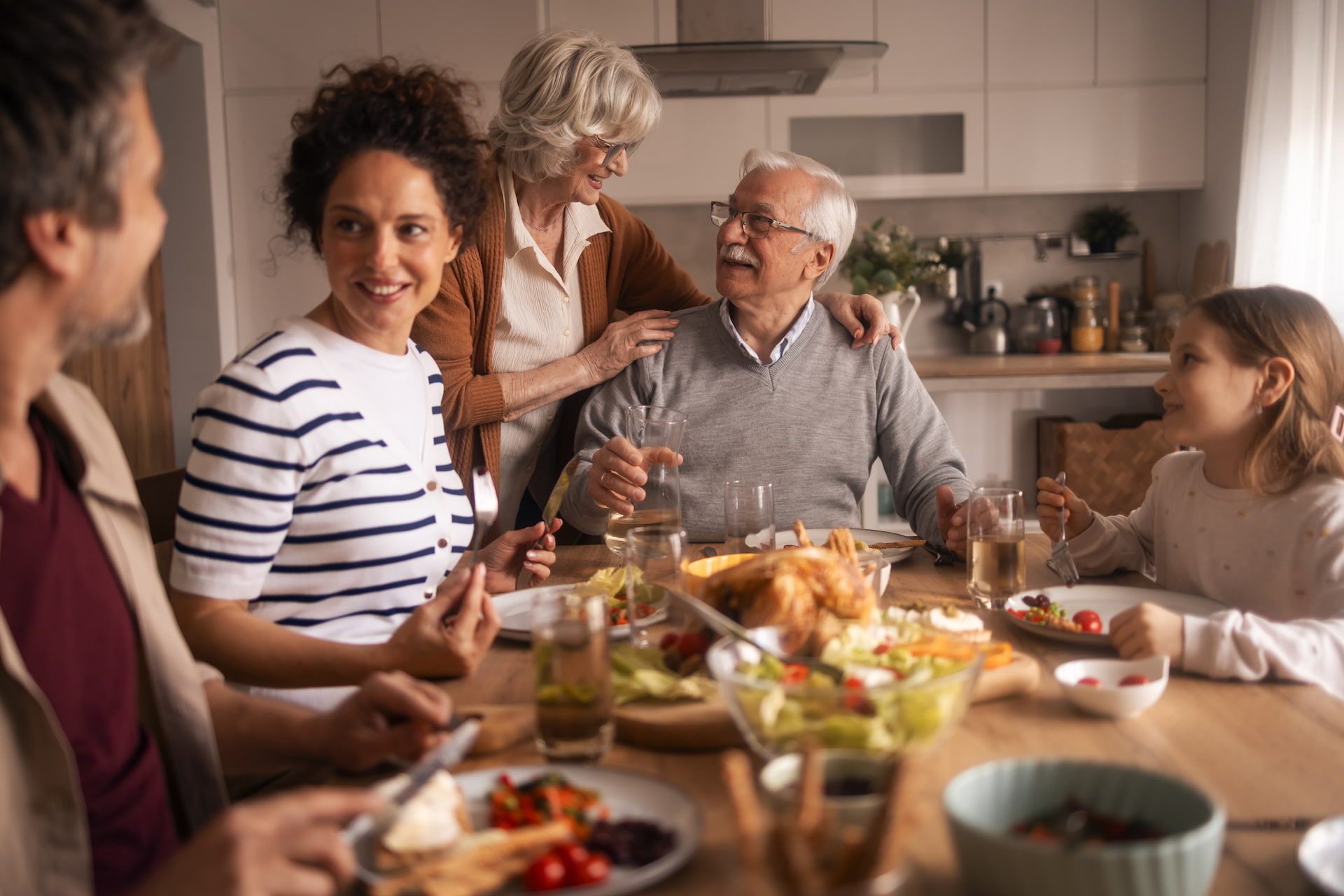 Fünfköpfige Familie isst gemeinsam am Tisch in heller Küche.