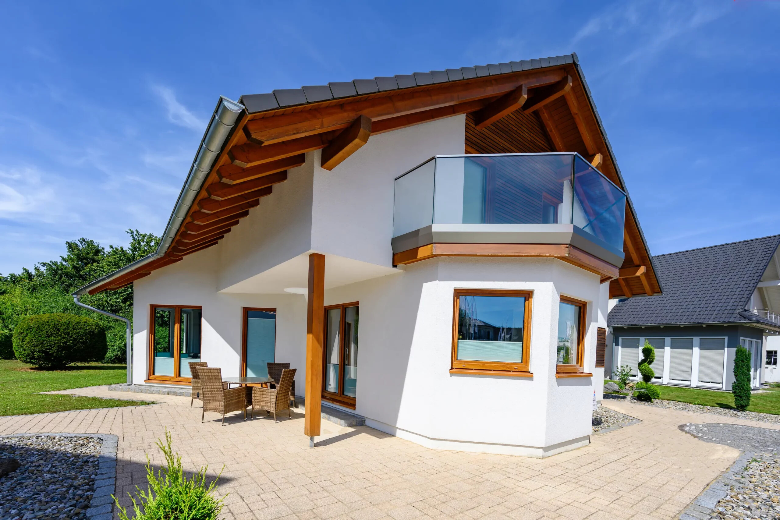 Zweistöckiges Haus mit vielen Fenstern und Glasbalkon draußen.