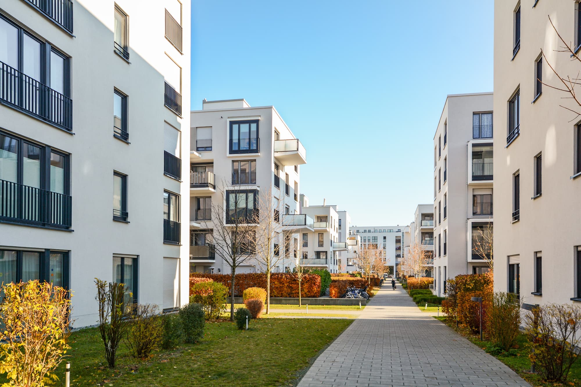 Moderne Apartments mit Balkonen und Weg an sonnigem Tag.