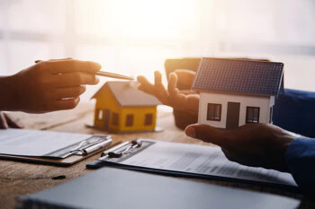 Mann hält Hausmodell in der Hand"