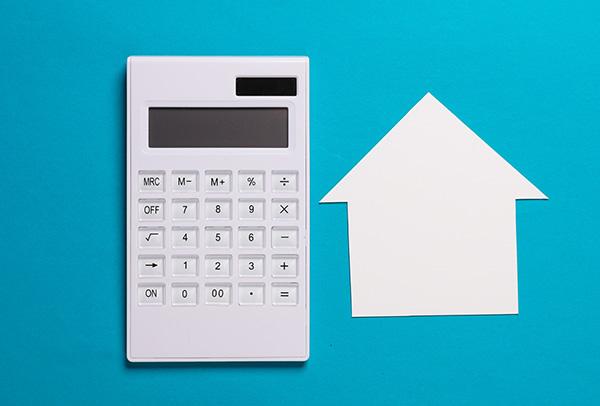 Papierhaus und Taschenrechner auf blauem Hintergrund