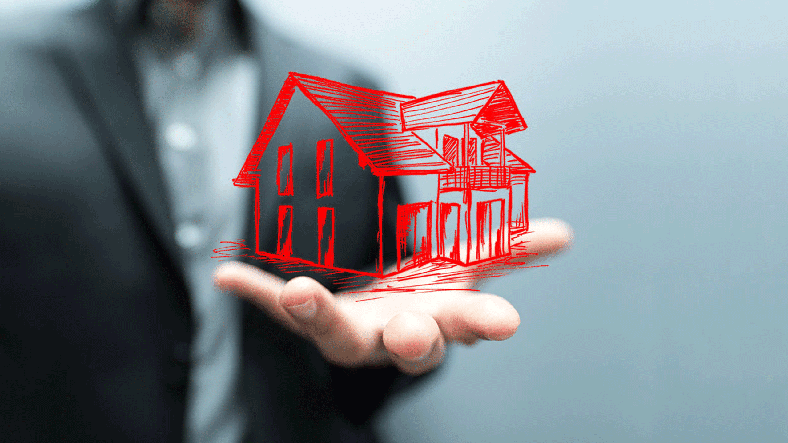 Person hält virtuelles rotes Haus