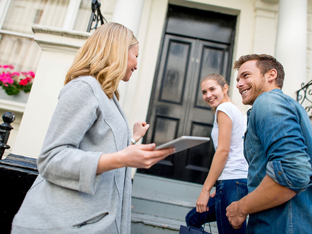 Immobilienmaklerin führt potenzielle Käufer durch die Besichtigung einer Immobilie