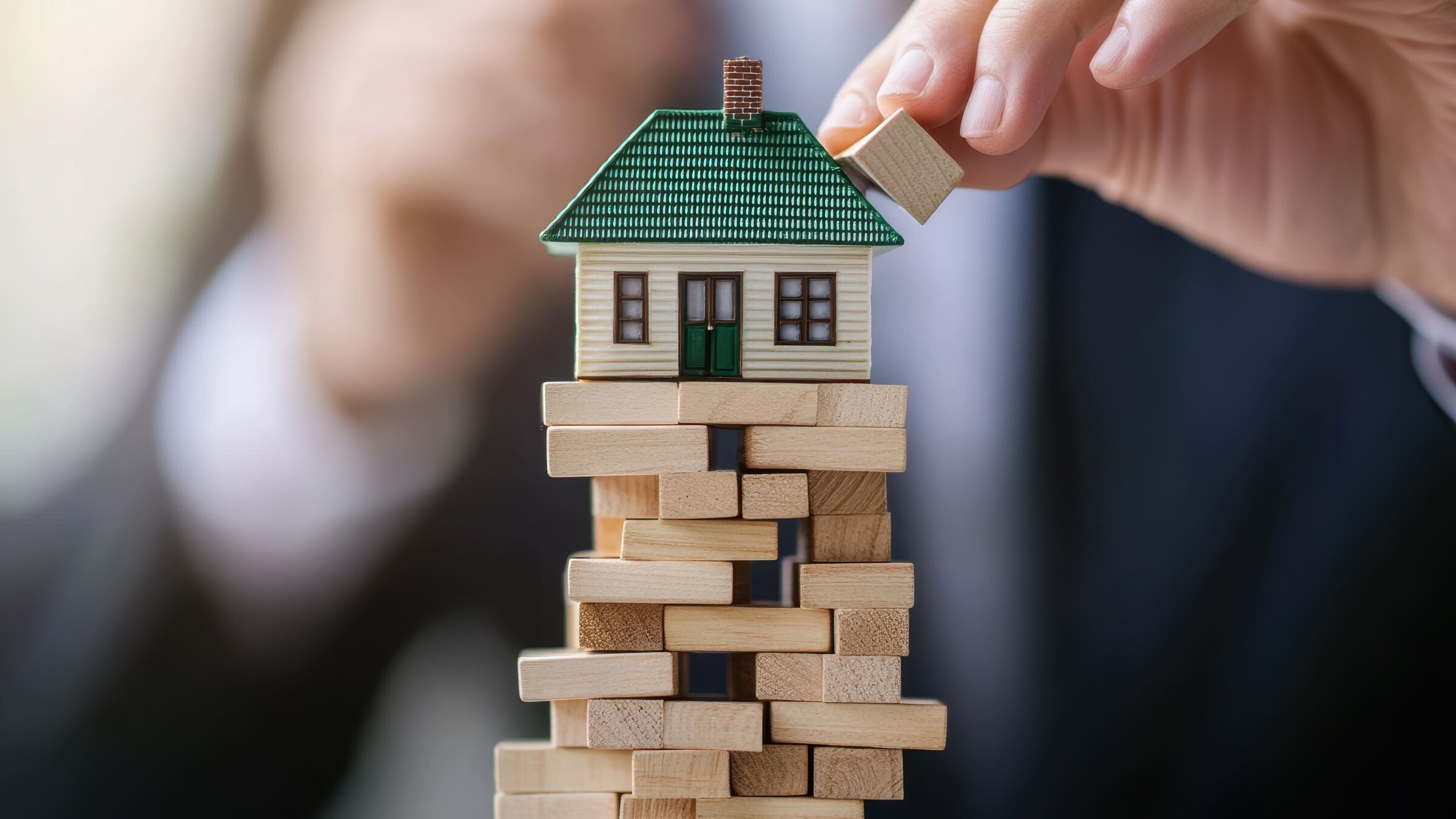 Modellhaus auf Jenga-Turm, Symbol für Probleme beim Immobilienverkauf